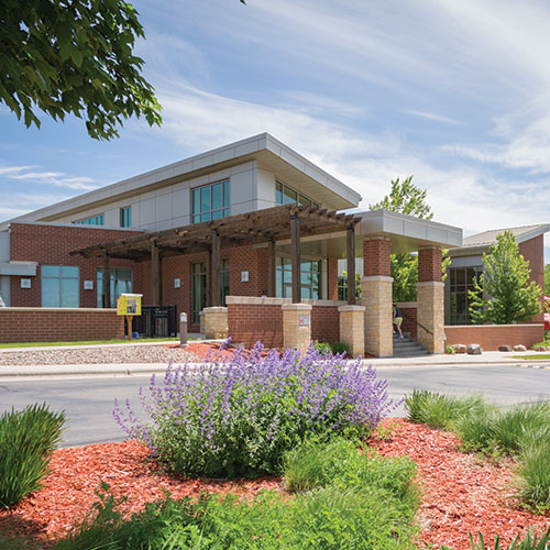 Front exterior of the Green Bay Kroc Center with purple flowers in the foreground.