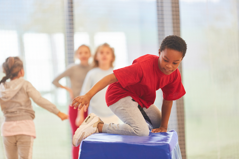 Children climb over padded obstacles in Ninja class.